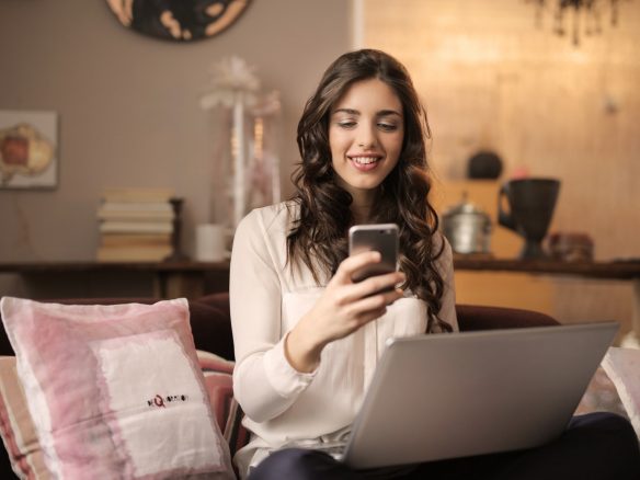 Woman using a phone and a laptop