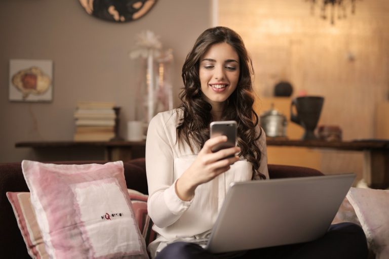 Woman using a phone and a laptop